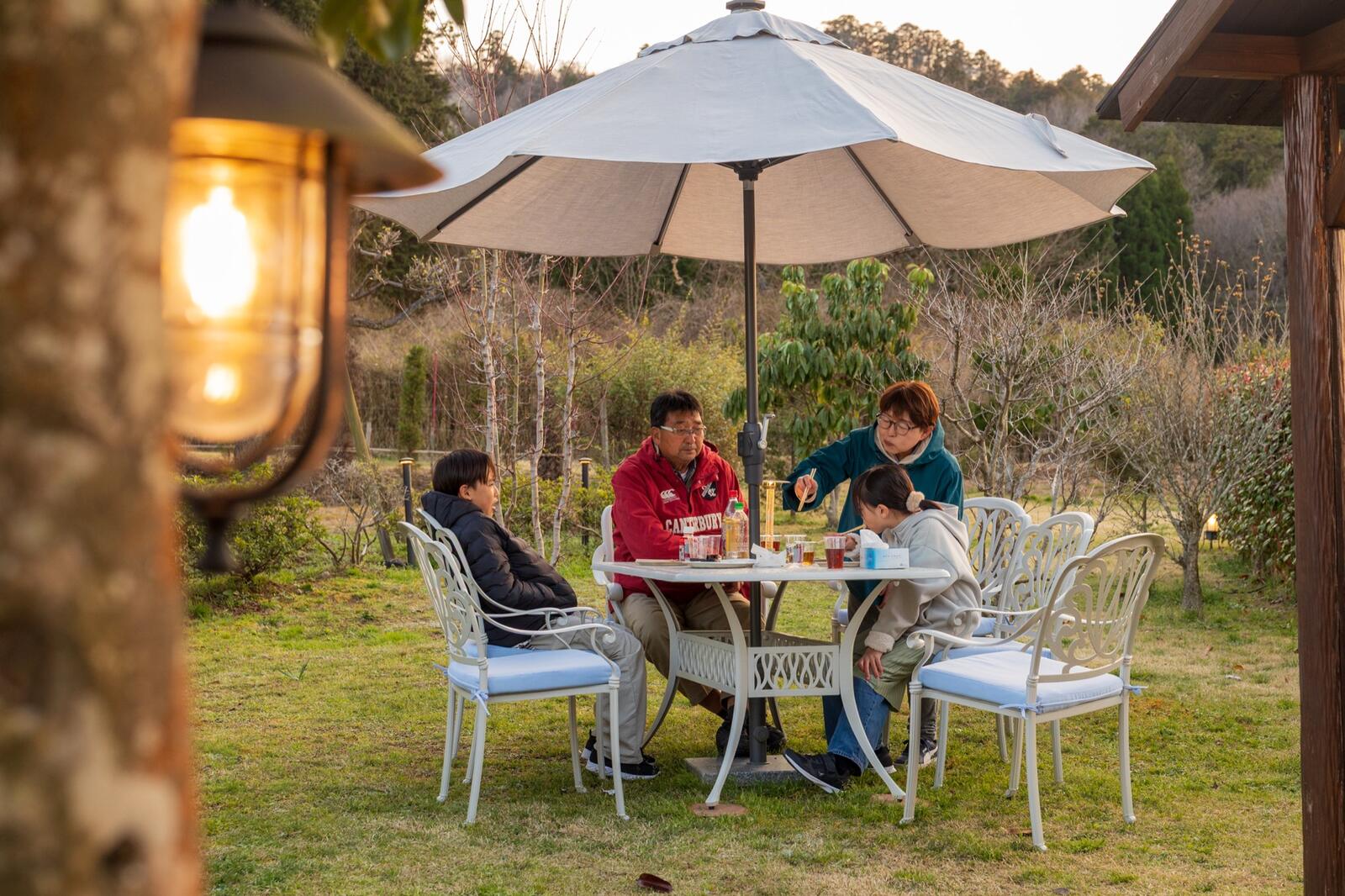 庭のガーデンテーブルで夕食を囲む祖父母と孫